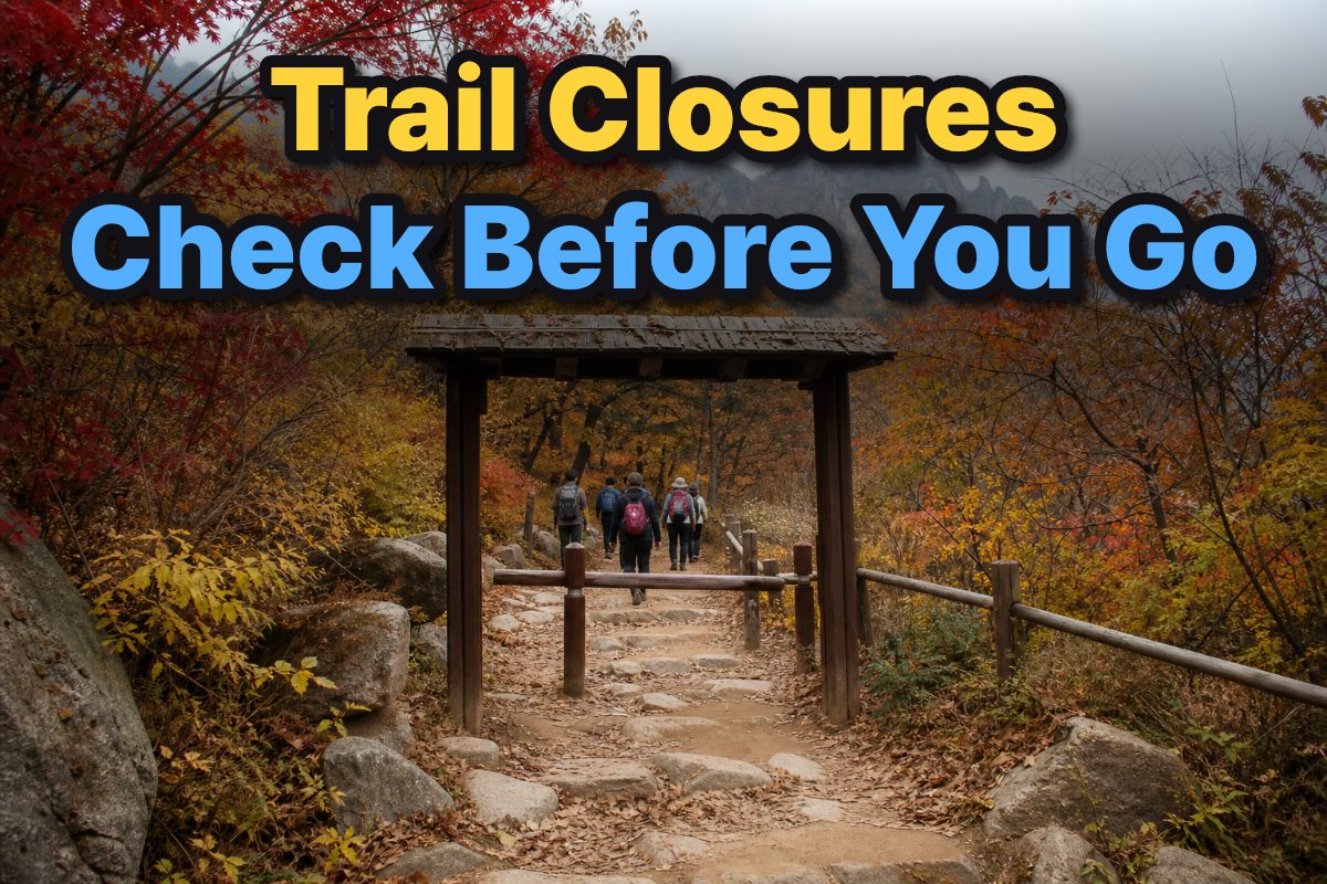 An autumn trail winds through a South Korean mountain forest beside a trail entrance.