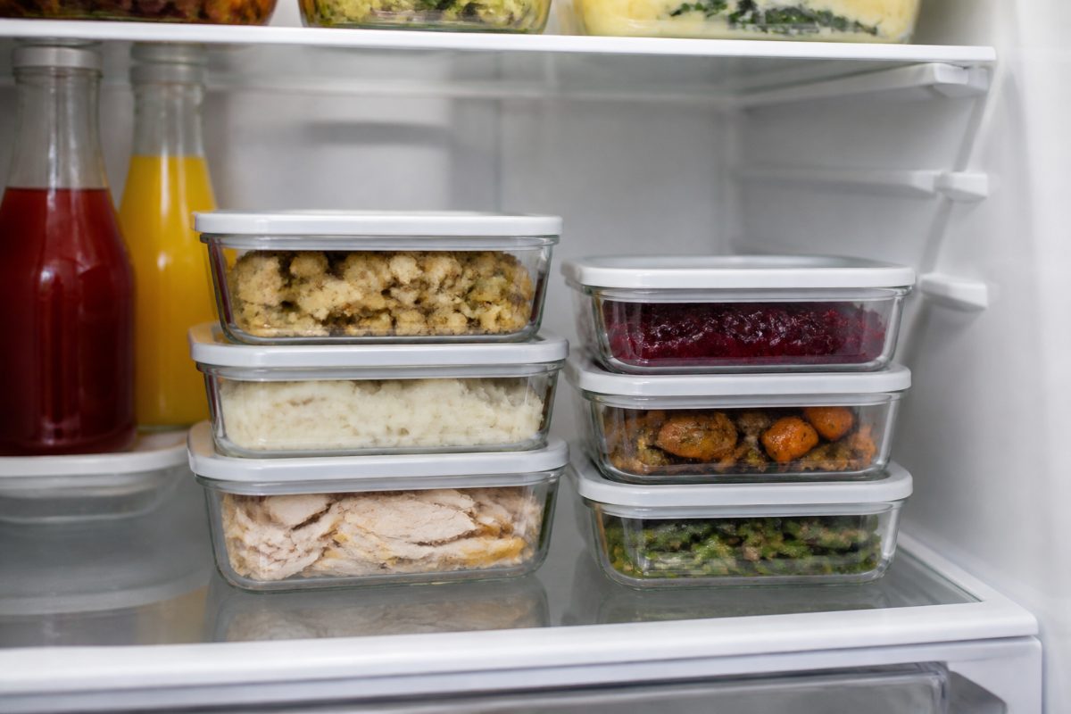 Shallow food containers filled with leftovers in a fridge.