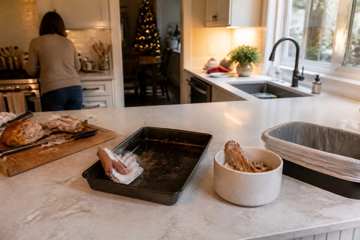 A greasy pan being wiped before washing, with food scraps kept out of the sink.