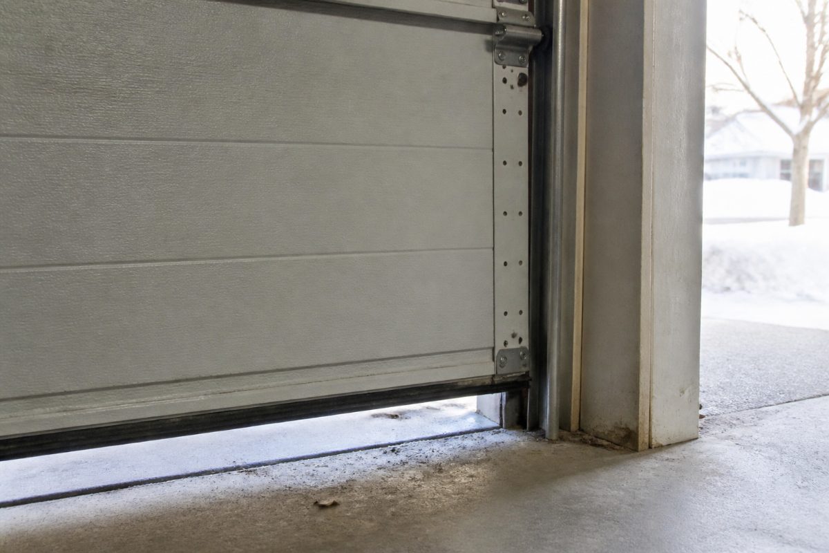 The bottom and frame seals of a garage door being inspected for gaps.