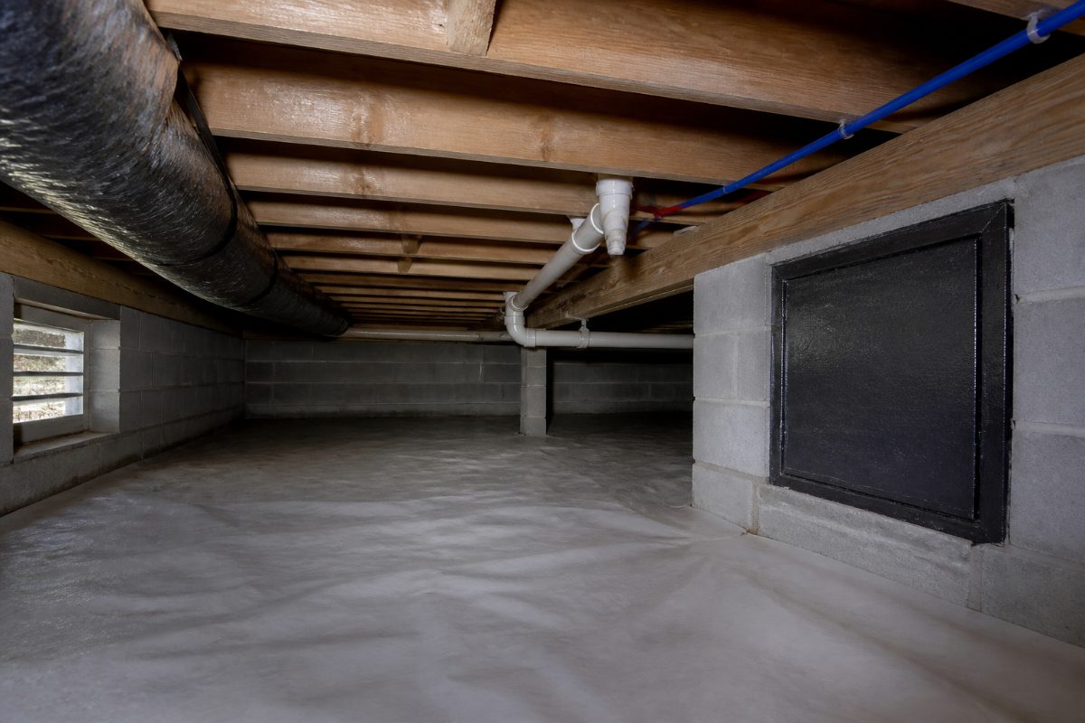 A crawl space inspection view showing vents, floor joists, and plumbing.