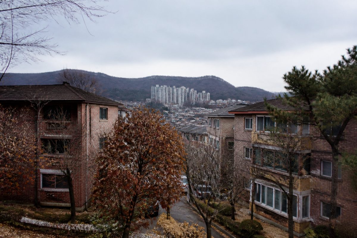 늦가을의 한국 주거지에 겨울을 앞둔 흐린 하늘과 아파트가 보입니다.
