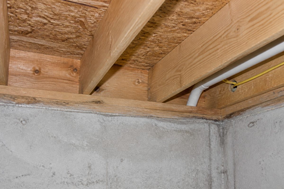The rim joist, sill plate, subfloor, and foundation connection inside a crawl space.