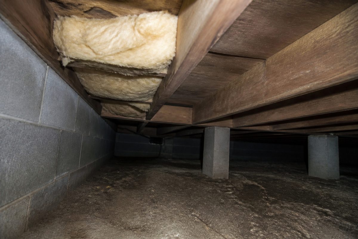 Compressed insulation beside crawl space framing near the exterior perimeter.