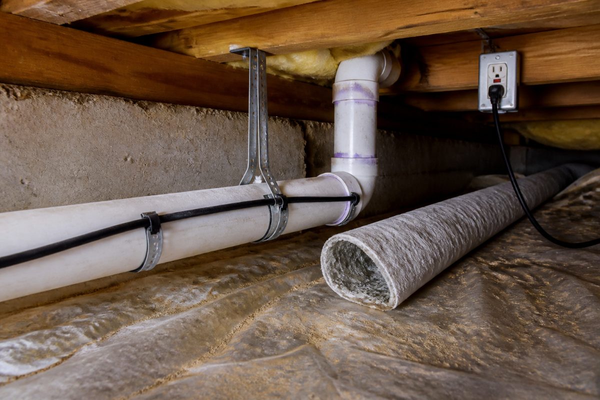 A pipe heating cable and nonflammable insulation in a crawl space near a GFCI-protected outlet.