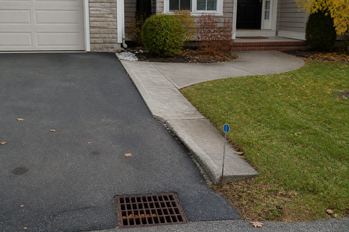 A driveway and walkway are inspected for pavement edges, drainage, and uneven spots.