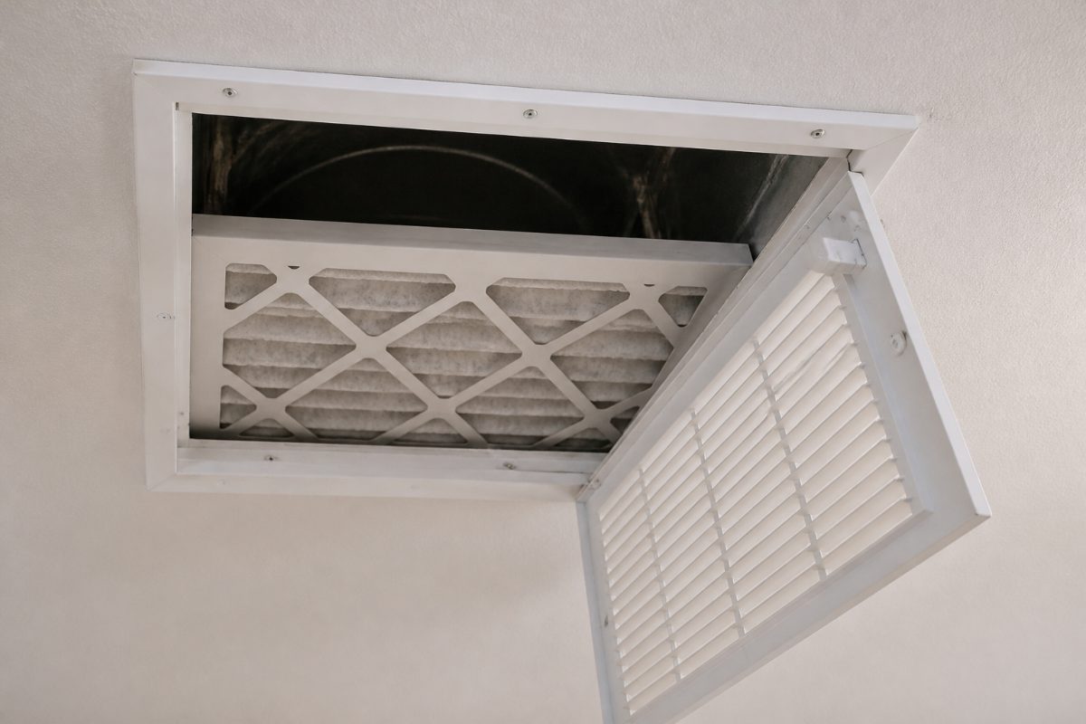 A furnace filter behind a ceiling return grille points into the duct and away from the room.