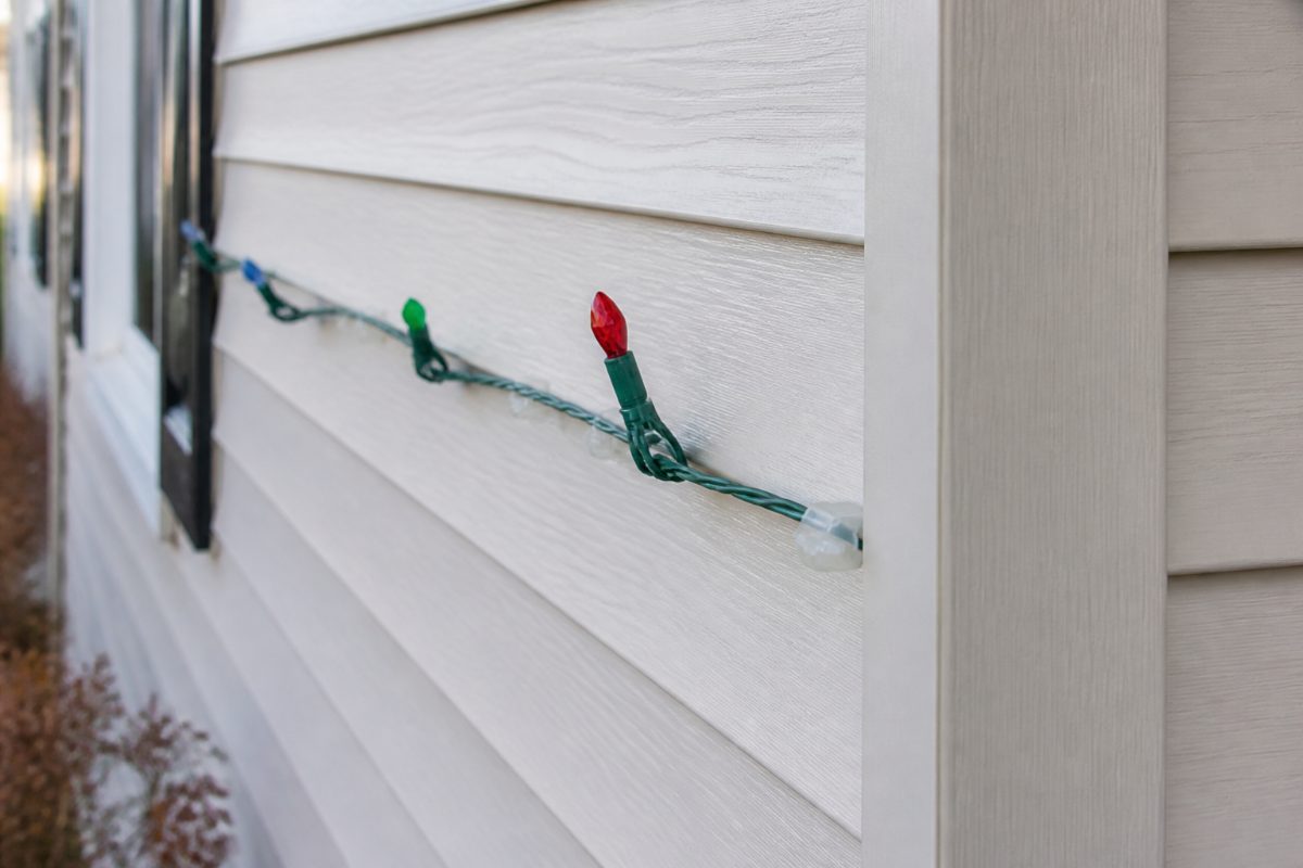A low-profile plastic clip supports a Christmas light strand without buckling vinyl siding.