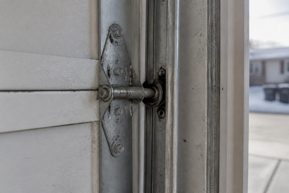 A garage door roller and hinge beside a cold-weather garage door lubricant.