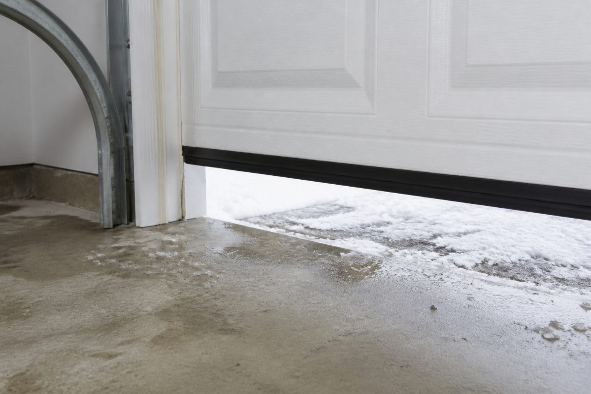 The bottom seal and clear floor area of a residential garage door prepared for winter.